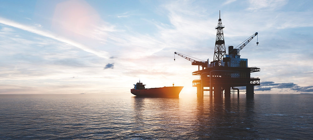 Offshore oil rig platform and supply ship at sunset