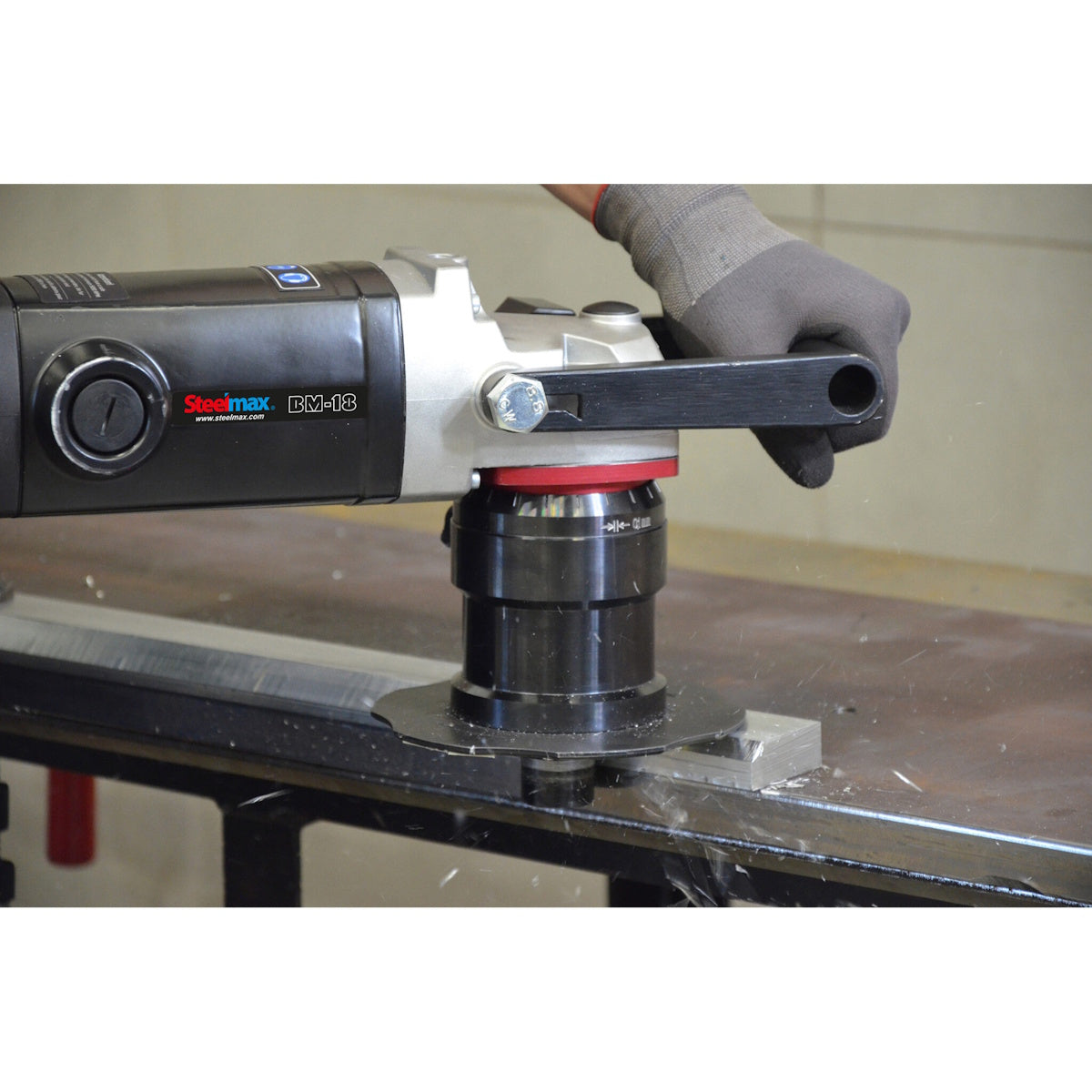 Steelmax 120V BM18 Portable Beveling Machine in action: a gloved hand prepares the edge of a metal plate with precision.