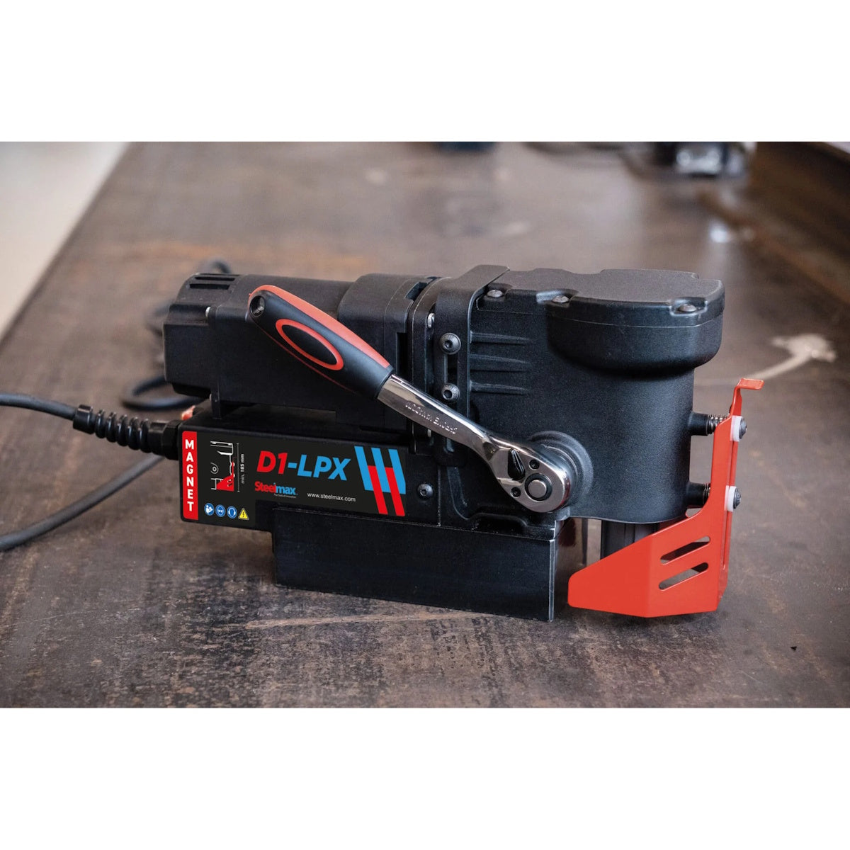 Steelmax 115V D1 LPX Low Profile Magnetic Drill SM-D1-LPX, black/red, sits on workbench with visible power cable.
