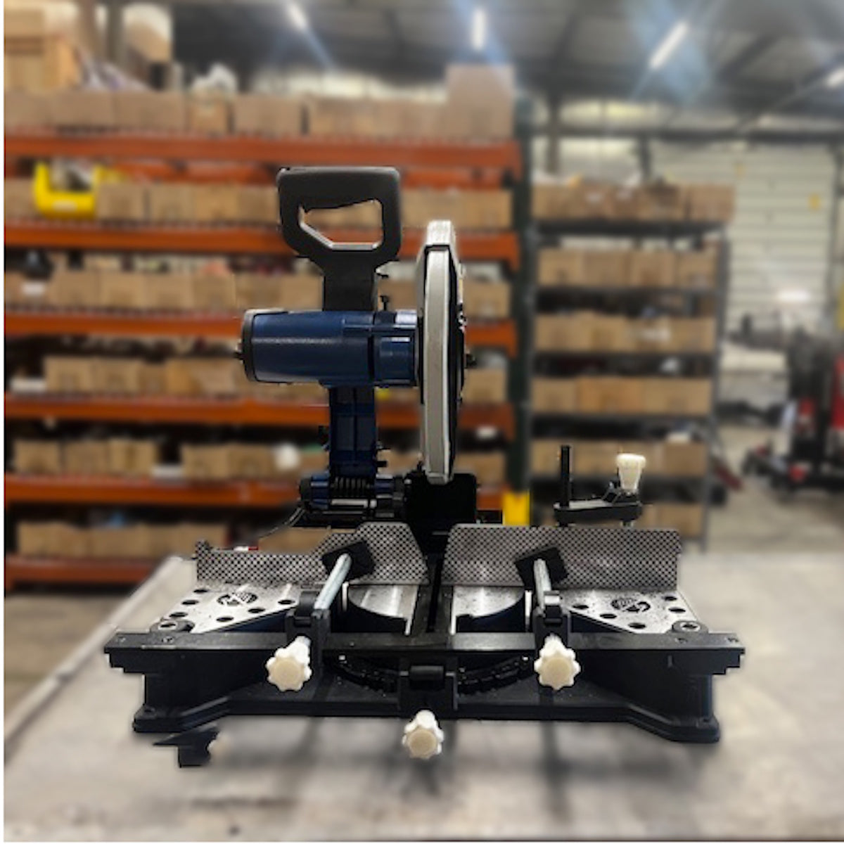 Steelmax 120V 14″ Metal Cutting Miter Saw SM-S-14-M on a workbench in warehouse with shelves of boxes.